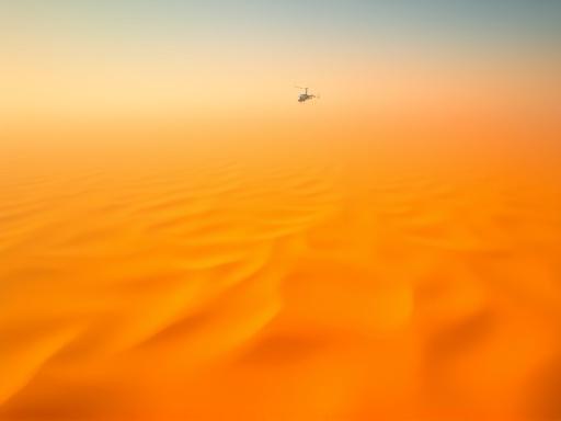 Vista aerea spettacolare da un elicottero che sorvola le infinite distese di dune dorate del deserto.